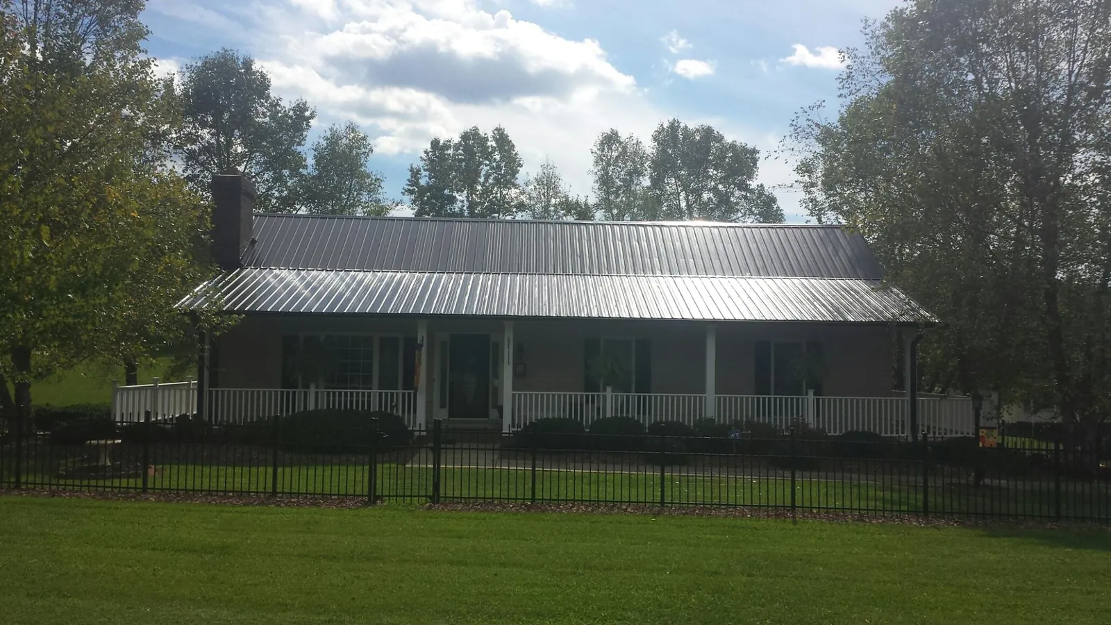 Gray metal roof on a brick ranch with a full width front porch — Gutter Guard Installation work by our crew in Stroh