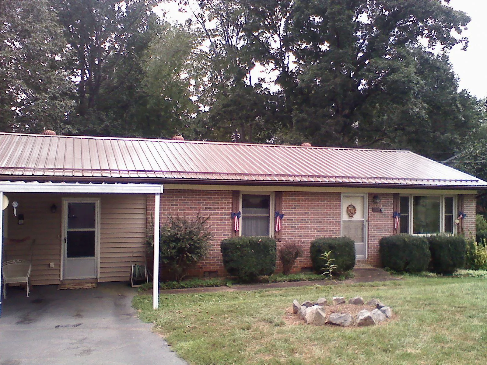 Bronze metal roof and carport on a brick ranch home — Roof Repair work by our crew in Stroh